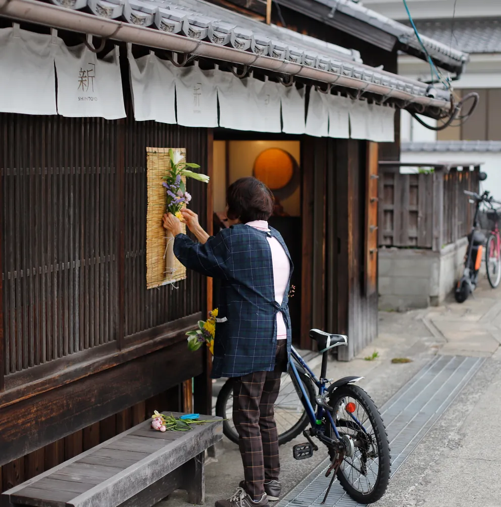A man at the window of a wooden shopfront, his bicycle beside him